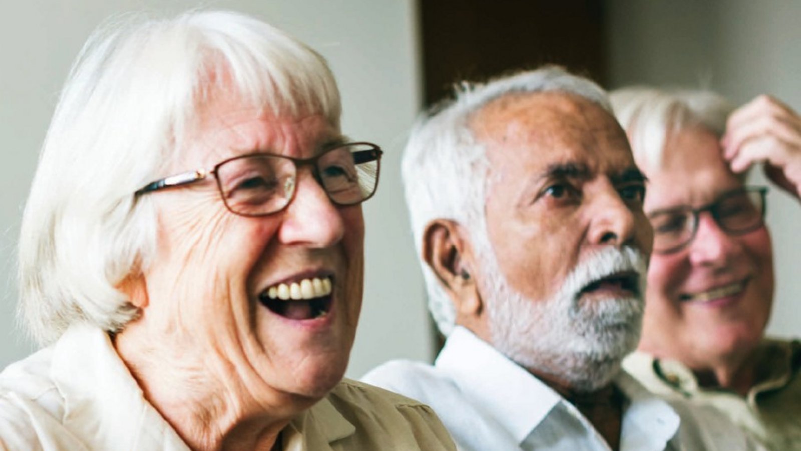 drei Senioren lachen in die Kamera. Sie sind sich ihres Alters bewusst und haben Freude am Leben.