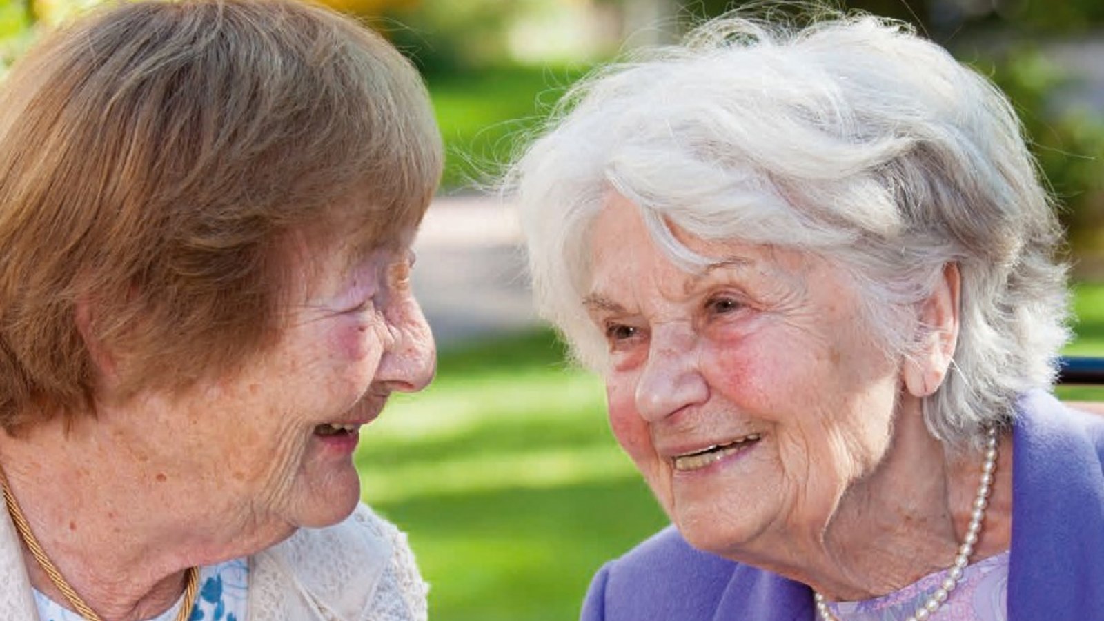 zwei Seniorinnen sitzen draußen und trinken gemeinsam ihren Kaffee.